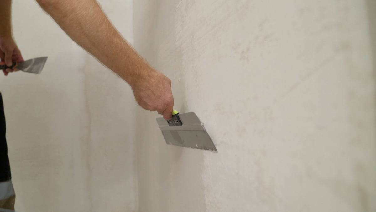Stukadoor brengt glad pleisterwerk aan op een muur in Oss