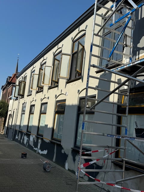 Historisch crème gekleurd pand met boogramen en steigers