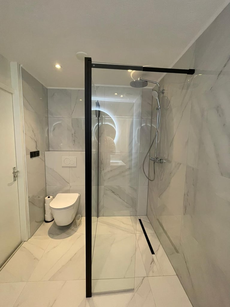 Marmerlook badkamer met glazen scheiding in Oss
