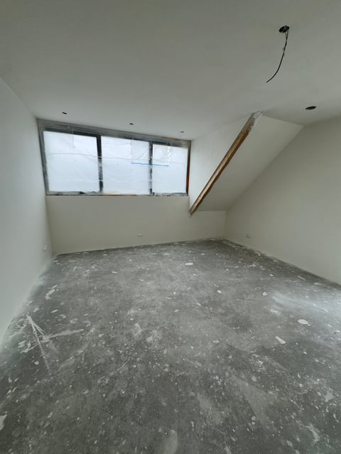 Lege ruimte onder constructie met betonnen vloer, witte muren en koperen buizen
