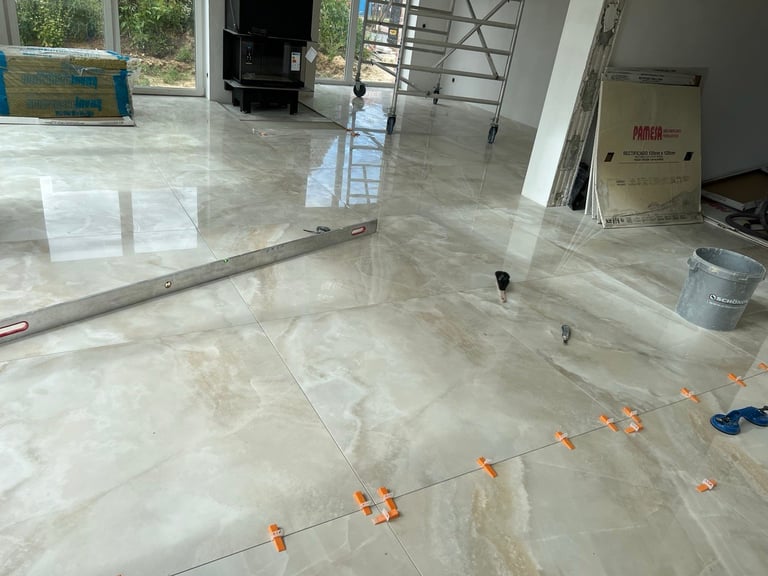 Interior construction space with polished concrete floor, orange floor clips marking measurements, and metal electrical conduit