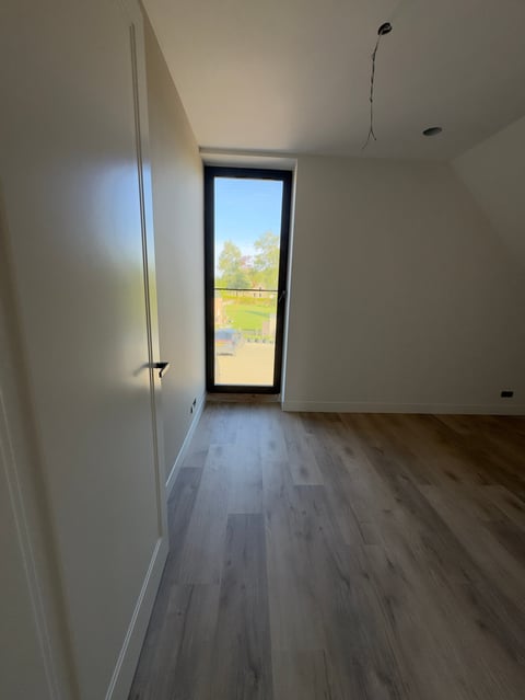 Ruimte met grijze houten vloer en glazen deur naar buiten