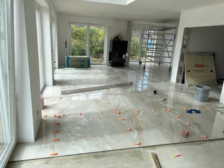 Empty interior room under renovation with plastic flooring, orange markers, and construction materials visible