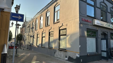 Geel historisch pand met grote ramen op Europese straat