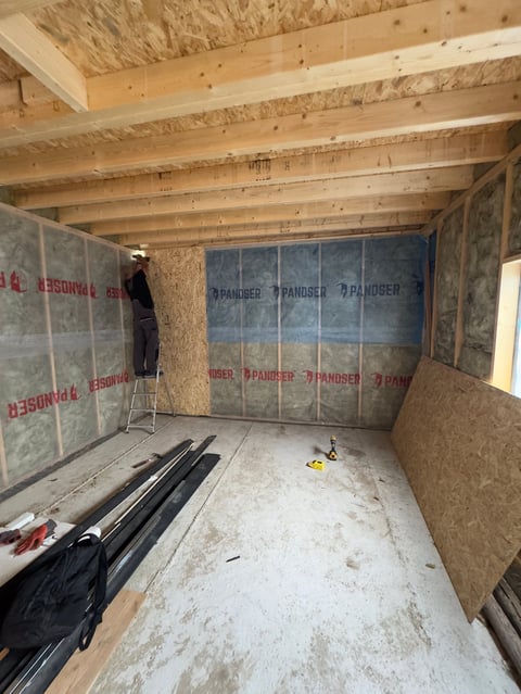 Interior of a room under construction with wooden beams and insulation boards
