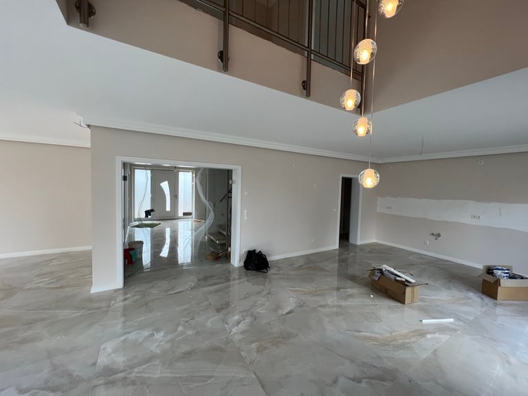 Modern empty commercial space with marble flooring, glass doors, pendant lighting, and white walls under construction